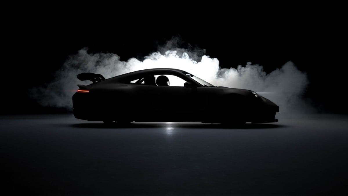 Silhouette of a sports car in profile against backlit smoke